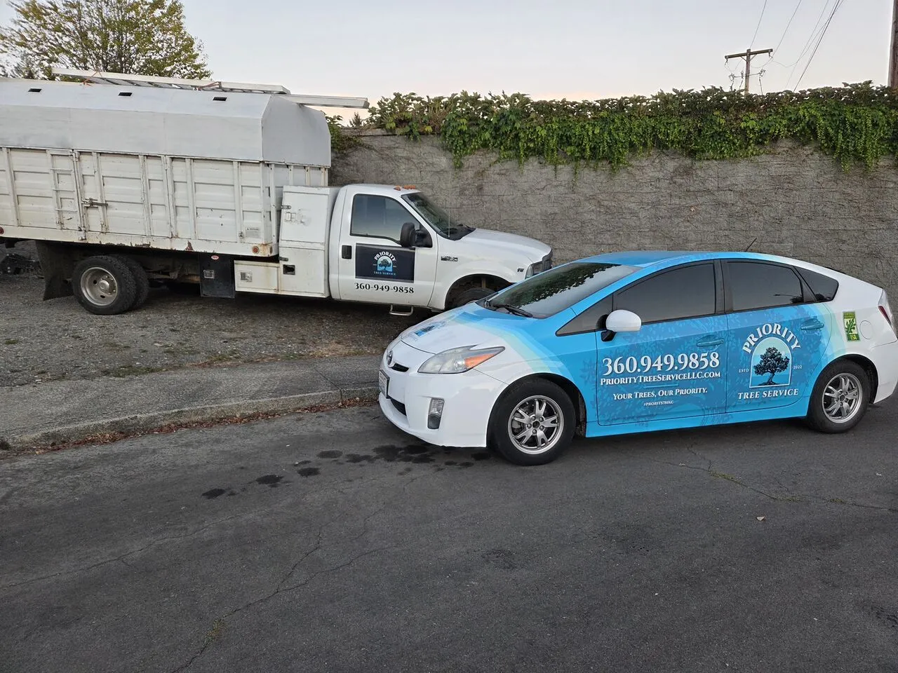 Priority Tree Service chip truck and branded car parked curbside for a job in La Center, WA