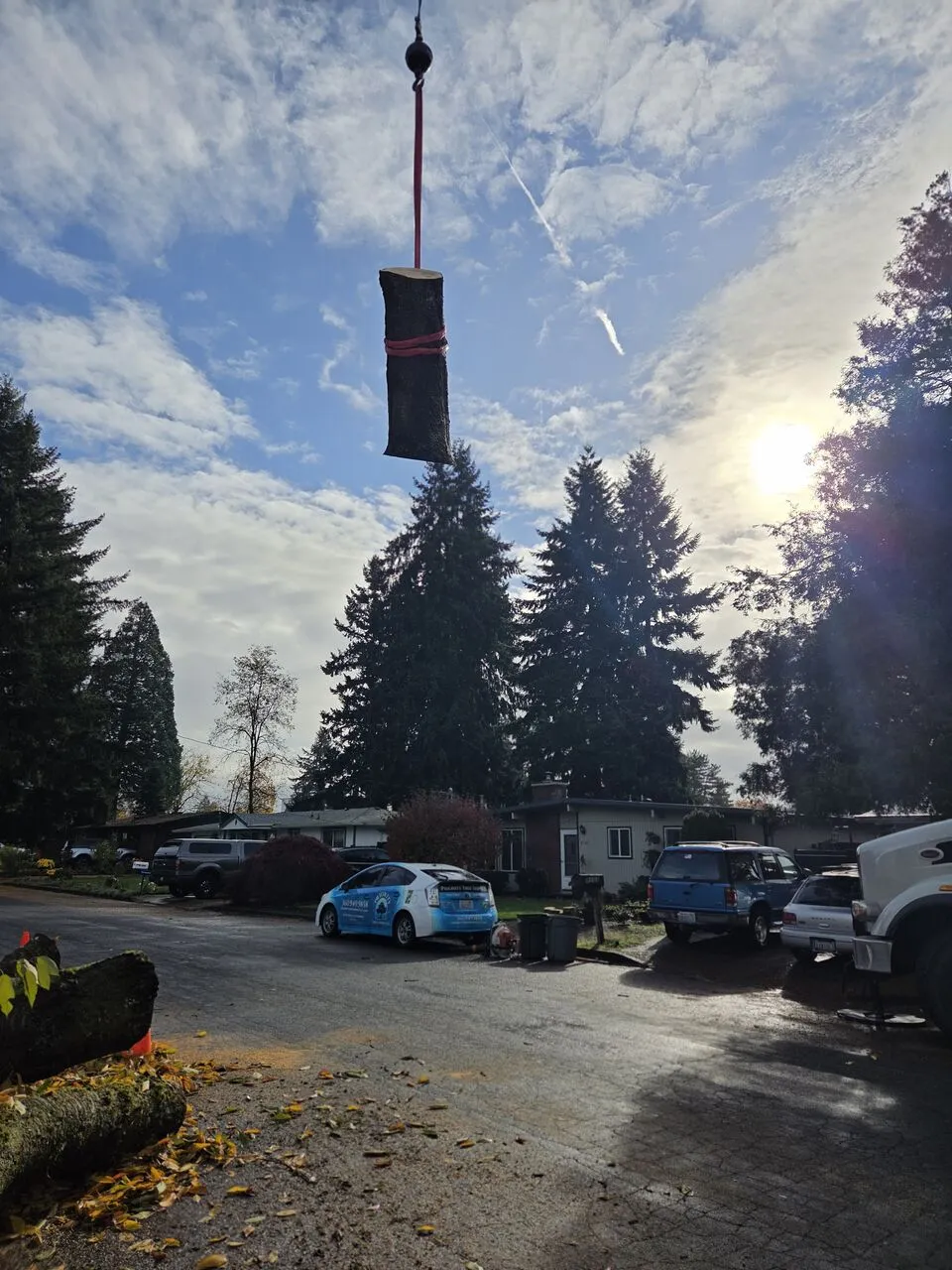 Crane lifting a rigged log section over a residential driveway in Ridgefield, WA