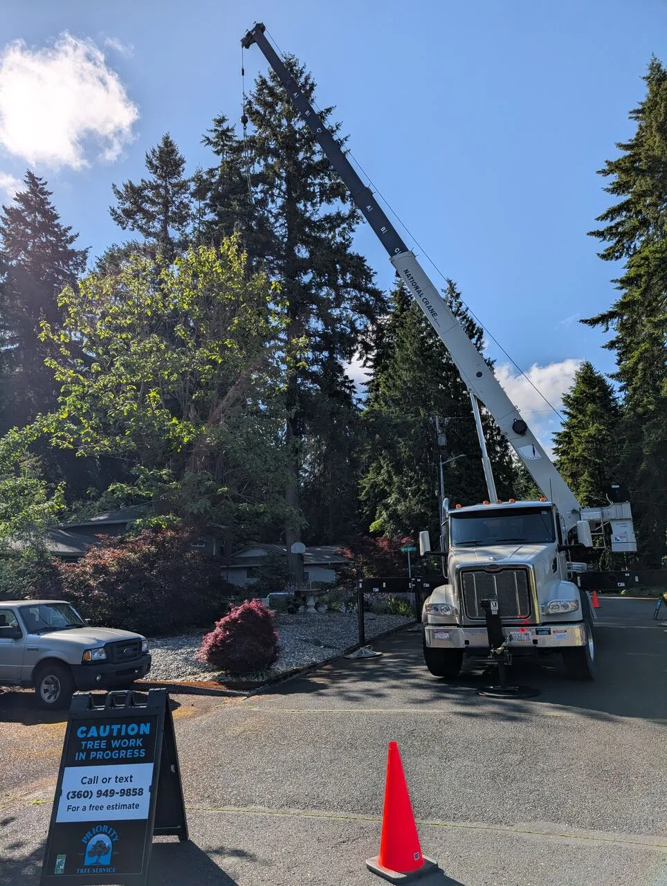 Crane truck and caution sign set up for a tall conifer tree removal in a Vancouver, WA neighborhood